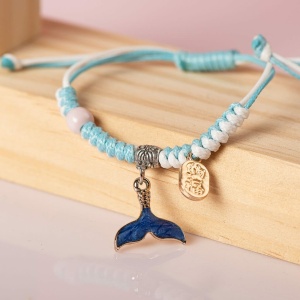 Gevlochten armband met hanger van zeedieren in blauw en wit, op een houten plankje