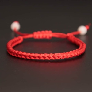 Armband van handgeweven rood touw op een zwarte achtergrond