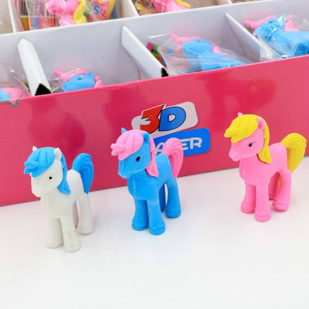 3 stuks witte, blauwe en roze eenhoornige gummen naast een roze doos op een witte tafel
