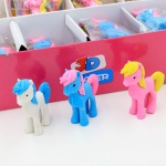 3 stuks witte, blauwe en roze eenhoornige gummen naast een roze doos op een witte tafel