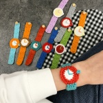 Gebreide wollen armband in de vorm van een gekleurd horloge om de pols van een vrouw met een grijze achtergrond