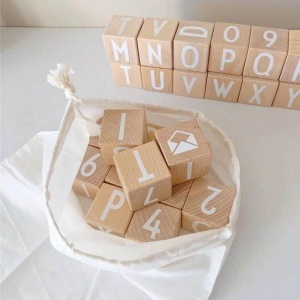 Houten alfabet speelgoed om in een witte zak op een witte tafel te nieten