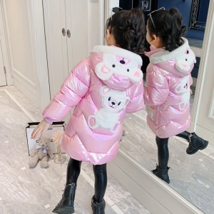 Lange, glanzende teddybeerjas met capuchon voor meisjes in roze met beer in de capuchon en op de rug op een meisje voor een spiegel