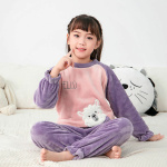 Pyjama van flanellen fleece met een schattig patroon voor kinderen in paars en roze op een meisje in een wit tapijt met een kussen op de rug