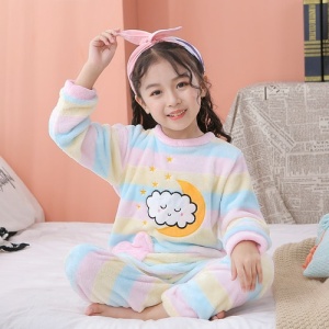 Fleece pyjama in een kleurrijk maanmotief voor kinderen met een wolkenmotief op de voorkant in een woonkamer op een wit tapijt