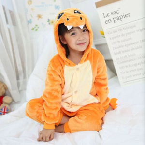 Schattige kinderpyjama in oranje met klein meisje op een bed in het wit
