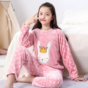 Een meisje draagt een polaire pyjama met een wit konijnenpatroon in bed