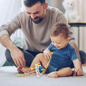 Montessori siliconen bijtspelletje voor baby's met een achtergrond, een vader met zijn baby