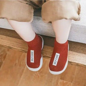 zien we de benen van een zittend kind met rode sokken met een wit label
