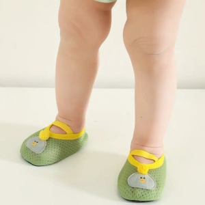 een baby staat met alleen zijn benen zichtbaar en draagt kleine, zachte, ademende groene slofjes