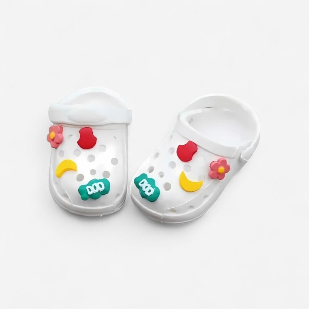 Witte mini klompjes voor Labubu-pop, Crocs-stijl met speelse decoratieve motieven, op witte achtergrond.